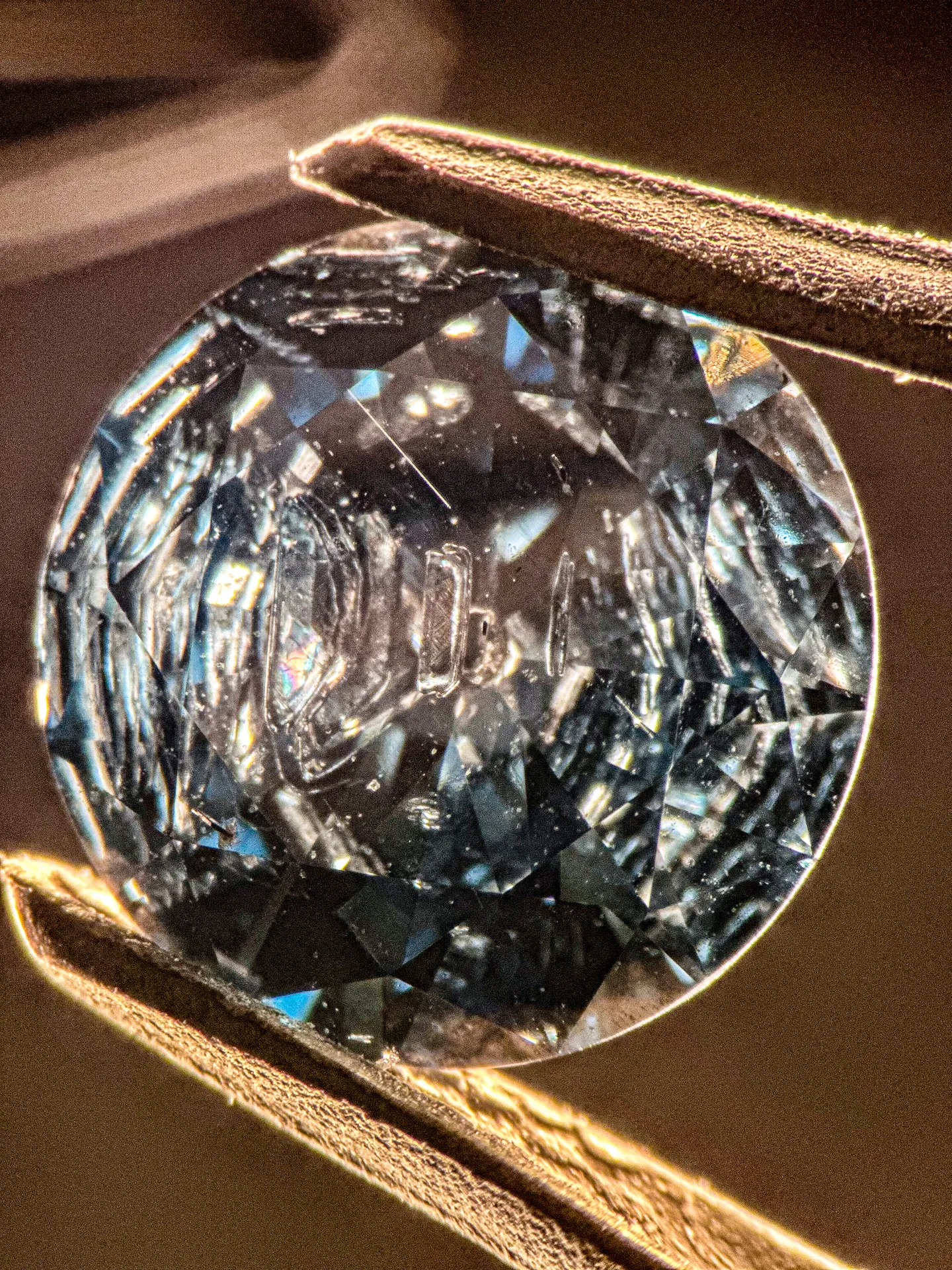 Blauer synthetischer HPHT-Diamant von oben, Dunkelfeld: mehrere längliche metallische Flussmitteleinschlüsse unter der